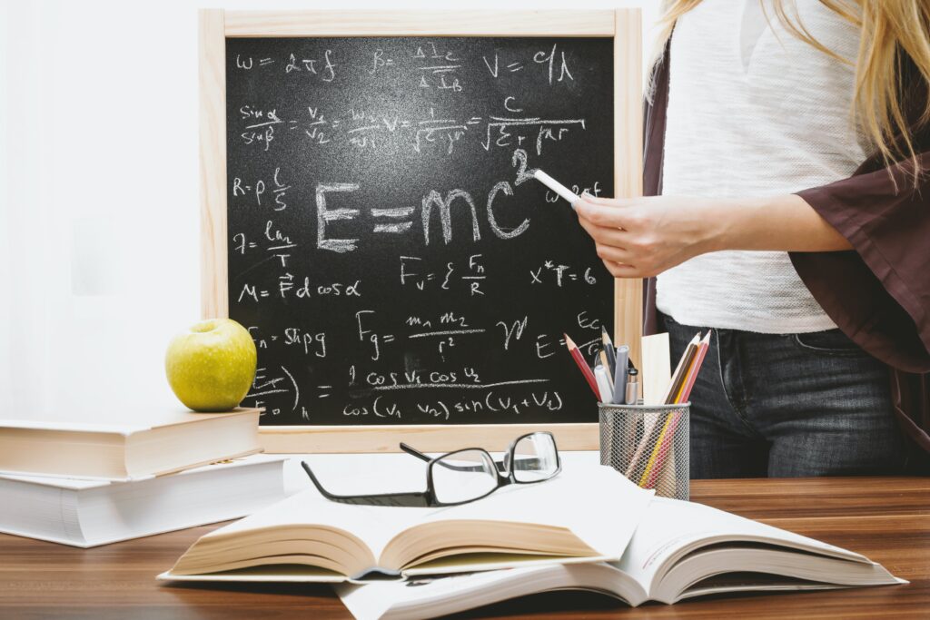 黒板に物理の公式を書いている人